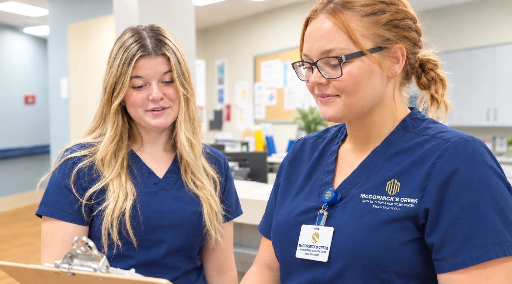 Two members of staff going over notes together at the nurses’ station
